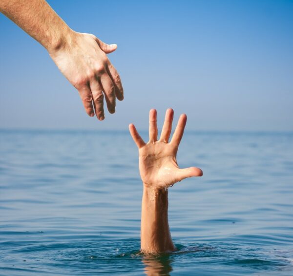 helping hand giving to drowning man in sea